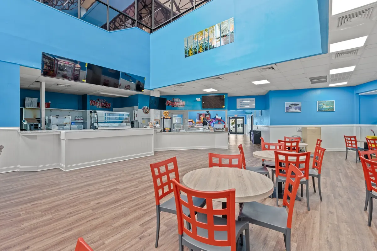 A vibrant dining space with bright blue walls, bold red chairs, a modern counter, and large screens for entertainment. The open layout encourages lively meals and group gatherings, emphasizing the property’s suitability for celebrations and casual get-togethers.
