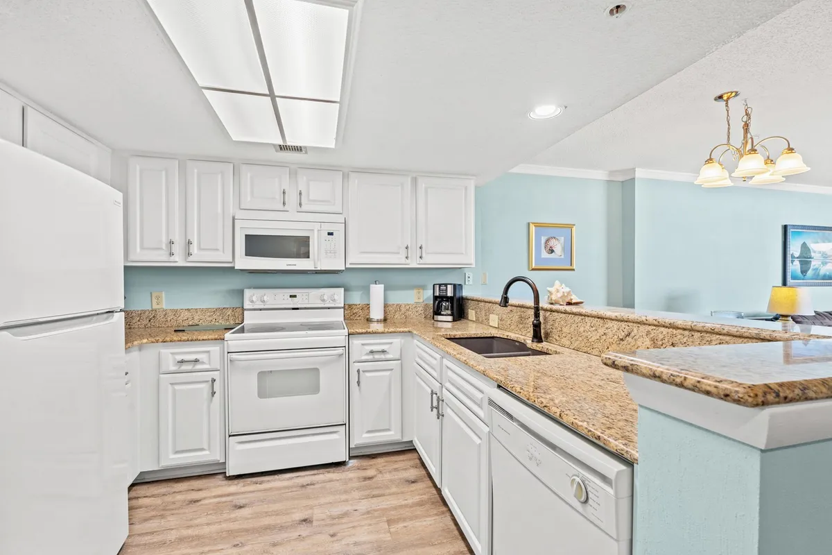 A bright and welcoming kitchen with striking granite countertops, crisp white cabinetry, and an array of modern appliances. The space is open and inviting, designed to accommodate multiple cooks and keep conversations flowing into adjacent living spaces.