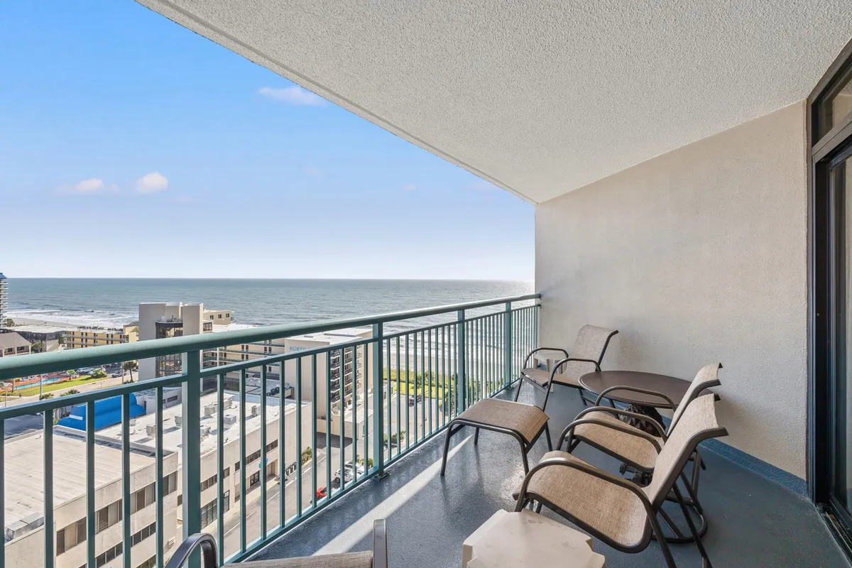This tranquil image highlights a private balcony with comfortable seating overlooking the sparkling ocean. Gentle morning sunlight bathes the area, suggesting the perfect place to enjoy coffee or cocktails while soaking in the ocean breeze and panoramic views.